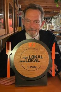 a man holding a wooden plate with a fork and knife at Pension und Restaurant Die Burg in Ehrenfriedersdorf