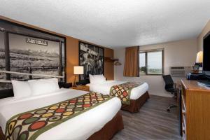 a hotel room with two beds and a desk at Super 8 by Wyndham Cheyenne WY in Cheyenne