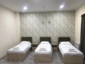 a room with three beds in a room at MAZZA Hotel in Tashkent