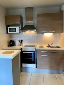 a kitchen with a stove and a microwave at Urban Home - 4 pers - Netflix in Eysines