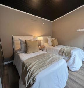 Cabañas de Montaña Armonías Lodge في لوس موليس: سريرين في غرفة ذات أغطية ووسائد بيضاء