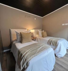 two beds in a room with white sheets and pillows at Summit Trip Winter Lodge in Los Molles