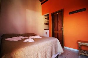 Cama en habitación con pared de color naranja en Pousada Oasis, en Olímpia