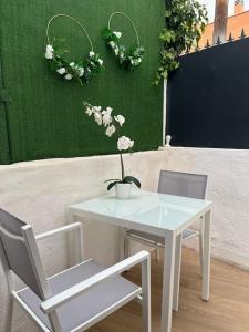 une table et des chaises blanches avec des fleurs sur un mur dans l'établissement LR IFEMA MADRID, à Madrid