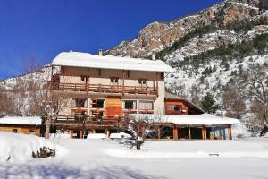 a large building with snow on it in front of a mountain at Hôtel Restaurant Gîtes Les 5 Saisons in Freissinieres