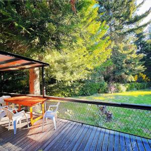 una terraza de madera con mesa y sillas. en Ruca Quimei Malek en San Carlos de Bariloche