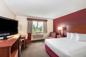 a hotel room with a bed and a flat screen tv at SureStay Plus Hotel by Best Western Litchfield in Litchfield