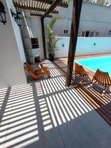 una terraza con 2 sillas y una piscina en The Guest House hostel en Balneário Gaivotas