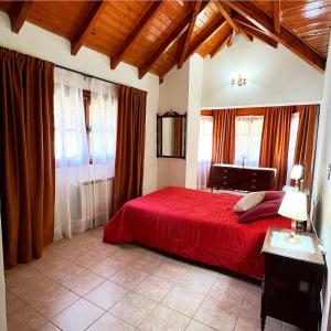 Un dormitorio con una cama roja y algunas ventanas en Ruca Quimei Malek en San Carlos de Bariloche