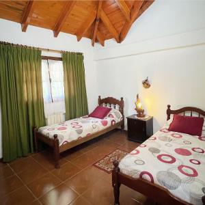 2 camas en una habitación con cortinas verdes en Ruca Quimei Malek en San Carlos de Bariloche