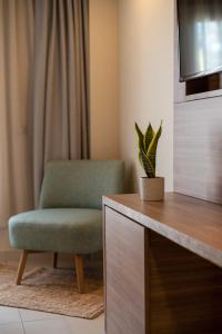 uma cadeira verde e uma planta num quarto em E-GEO Easy Living Resort em Marmari