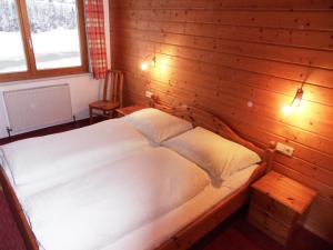 ein Schlafzimmer mit einem großen Bett an einer Holzwand in der Unterkunft Haus Konzett in Dalaas