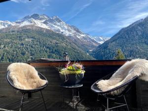 2 sillas en un balcón con vistas a las montañas en Haus Diel - Premium Apartments mit Küche, en Pettneu am Arlberg
