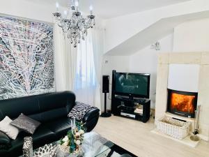 a living room with a black leather couch and a television at Apartmán Residenz in Poprad