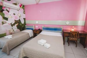 two beds in a room with pink and purple walls at Hotel Pousada Vovô Zinho in Siqueira Campos