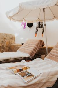 a bed with an umbrella and a magazine on it at casademeli ¡Garden and 5 min walk to the beach! in Las Playas