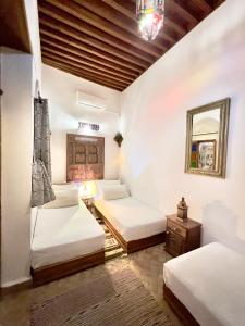 a room with three beds and a mirror at Dar Bhija in Fez