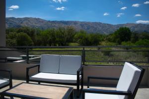 two chairs and a table on a balcony with mountains at Monteolivos Home & Suites in El Rincón
