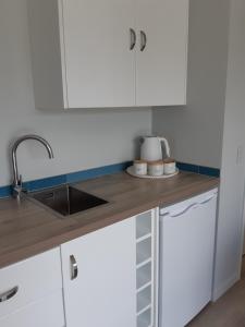 a kitchen with white cabinets and a sink at Seascape Hideaway Pohara in Pohara