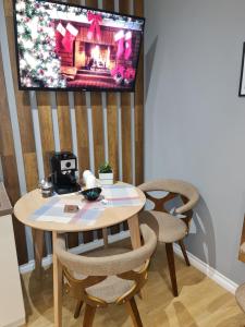 a table and chairs with a television on a wall at Sunny Apartment - Blloku Tirana, near Lake in Tirana