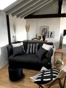 a living room with a black couch with pillows at Appartement dans le Vieux Mans in Le Mans