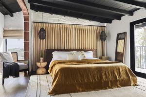 a bedroom with a large bed with a gold blanket at Television Host and Designer Bobby Berk Invites You To His Desert Oasis in Palm Desert