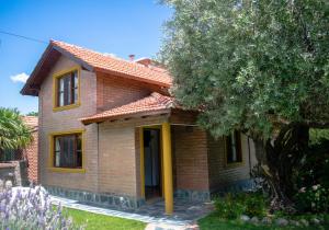 una casa de ladrillo con una puerta amarilla y un árbol en Cabañas Monteolivos en Merlo