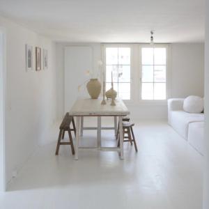 ein weißes Wohnzimmer mit einem Tisch und einem Sofa in der Unterkunft NI FRAVI Design-apartments, station Interlaken West in Interlaken