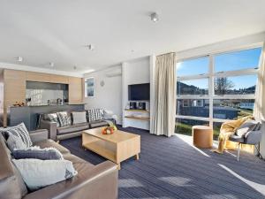 a living room with a couch and a table at Marina Gem - Lakefront 3 Bedroom Apartment in Queenstown