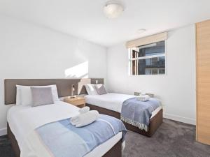 a bedroom with two beds and a window at Marina Gem - Lakefront 3 Bedroom Apartment in Queenstown