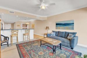 a living room with a couch and a table at Treasure Island 707 - Gulf front, sunset views, heated resort pool & hot tub! in Panama City Beach