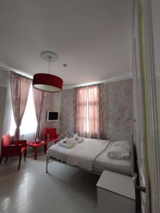 um quarto com uma cama e uma sala de estar com cadeiras vermelhas em Citalna Rooms em Bitola