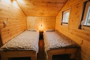 a bedroom with two beds in a log cabin at Domki Rower-Narty-Leżak - całoroczne, niezależne, taras, grill, zadaszone jacuzzi, ognisko, duży teren, blisko las, trasy rowerowe single-track, piesze wędrówki, narty in Świeradów-Zdrój