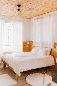 1 dormitorio con 1 cama grande y cortinas blancas en Tobiana Desert Lodging Negev en ‘Ezuz