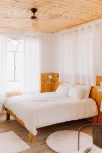 una camera da letto con un letto grande con tende bianche di Tobiana Desert Lodging Negev a ‘Ezuz