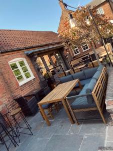 a patio with a wooden table and a couch at The Wheatsheaf Pub, Kitchen & Rooms in Bingham