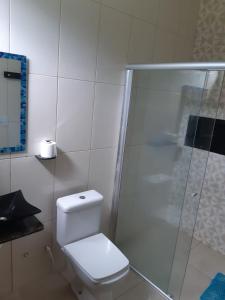 a white bathroom with a toilet and a shower at Chalé Estância da Mata Nobres MT in Nobres