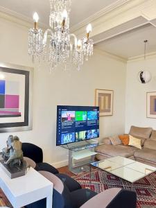 a living room with a chandelier and a large tv at Apartamento en Bilbao (La Merced, Pleno centro) in Bilbao