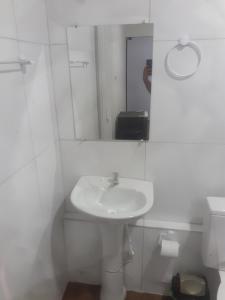 a white bathroom with a sink and a mirror at Hospedagem da barra suites,praia barra grande,caminho de moises e antunes in Maragogi