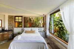 a bedroom with a bed and a large window at Feiticeira Guesthouse in Ilhabela