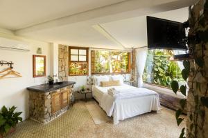 1 dormitorio con 1 cama, chimenea y TV en Feiticeira Guesthouse, en Ilhabela