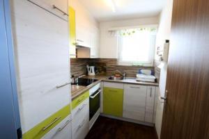uma pequena cozinha com armários brancos e uma janela em Near ski slopes 2 bedrooms apartment with balcony em Saas-Fee