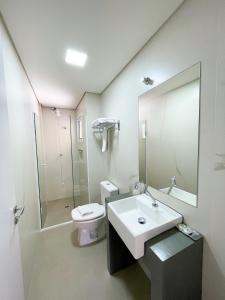 La salle de bains est pourvue d'un lavabo, de toilettes et d'un miroir. dans l'établissement Residencial Casa Flora - Centro de Bombinhas SC, à Bombinhas