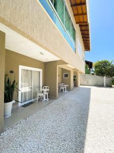 a building with a patio with chairs and a table at Residencial Casa Flora - Centro de Bombinhas SC in Bombinhas