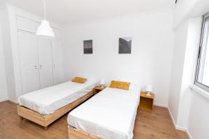 two beds in a room with white walls and wood floors at AL Cacém in Paiõis