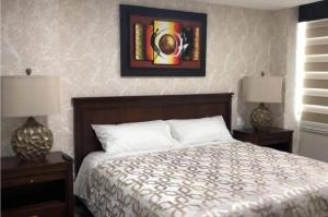 1 dormitorio con 1 cama con 2 lámparas y una foto en la pared en QUO 601 Lujo Confort Seguridad en Guayaquil