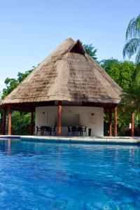 a hut with chairs and a swimming pool at Residencial Bali Casa Mariposa in Playa del Carmen
