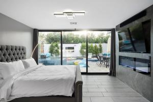 a bedroom with a bed and a tv and a patio at Luxury Villa 5mins to Old Town w Pool Fire pit and BBQ in Scottsdale +60 photos