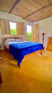 a bedroom with a large bed with a blue blanket at Finca Ecoparaiso in Ibagué