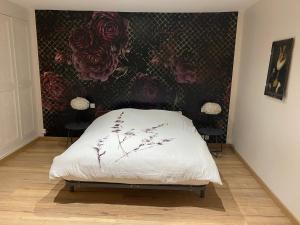 uma cama num quarto com uma parede floral em Propriété en bord de Sèvre em Niort
